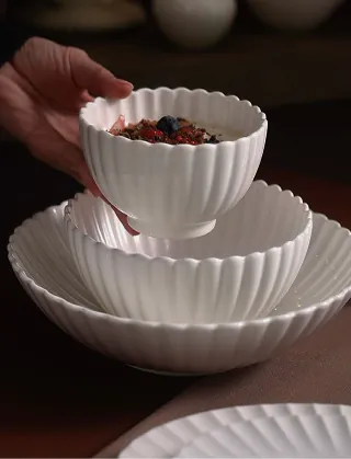 Hand placing white porcelain bowls and plates on a table