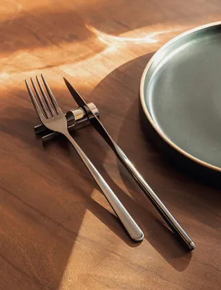 Fork and knife beside a ceramic plate